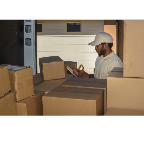 Man lastar paket i skåpbil utanför garage.