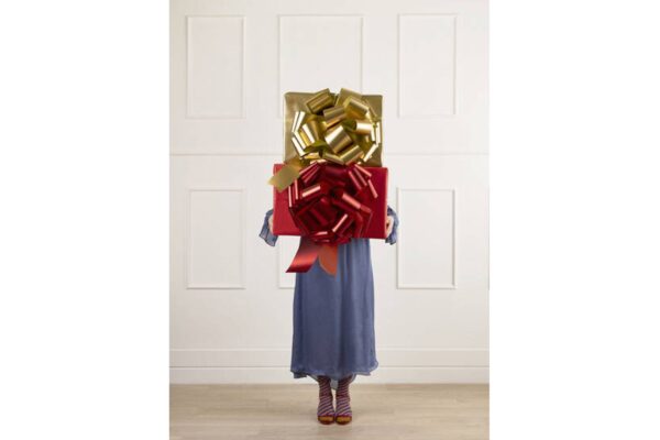 Person bär stora inslagna presenter, färgglada strumpor.