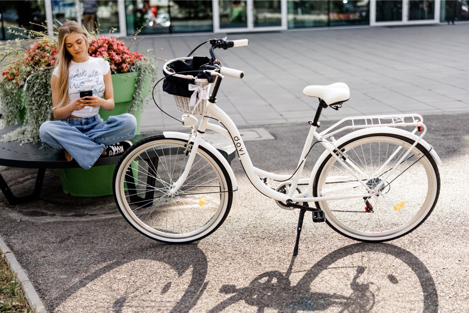 Kvinna med mobil bredvid vit cykel utomhus