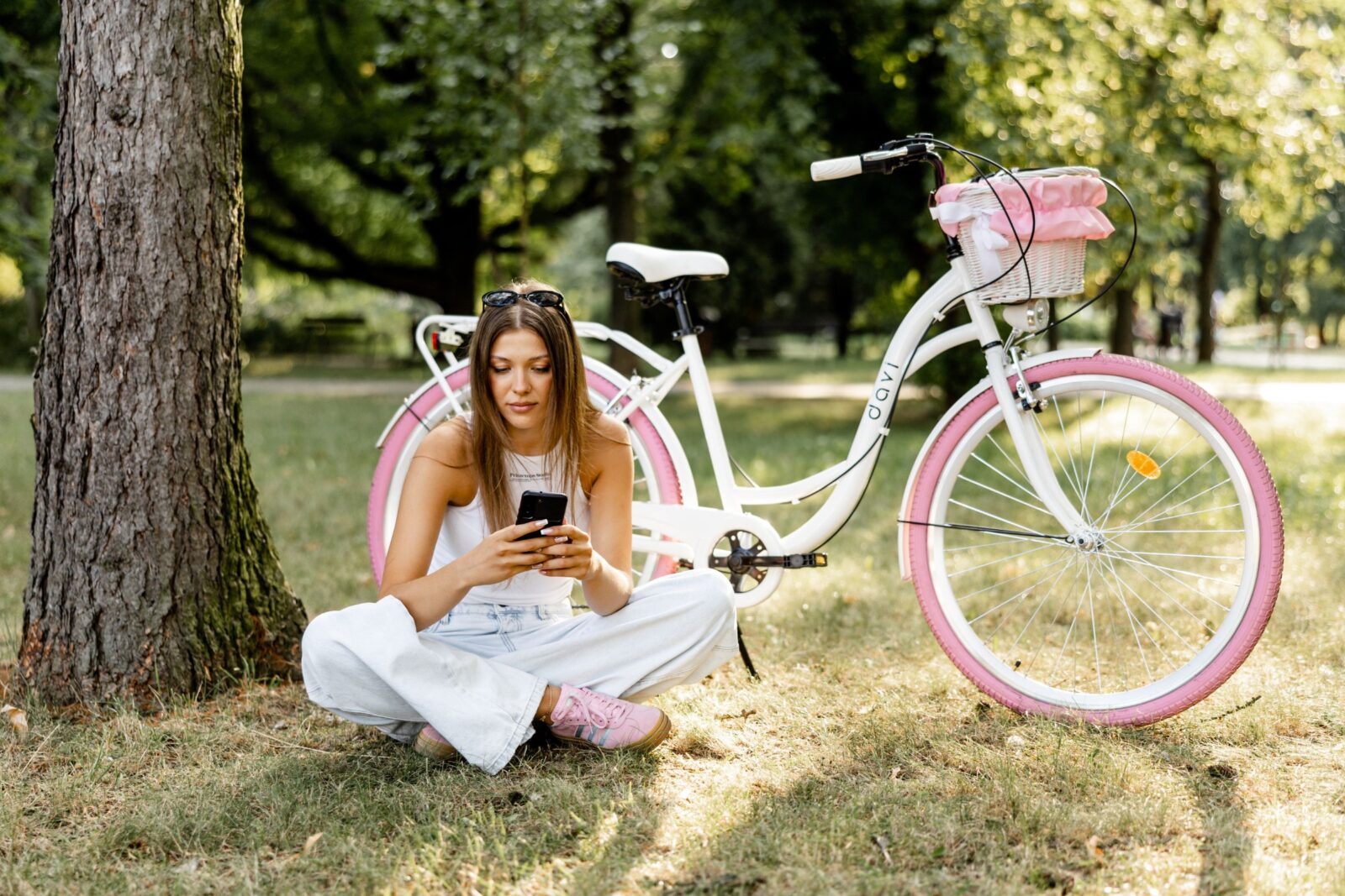 Kvinna med mobiltelefon bredvid cykel i park