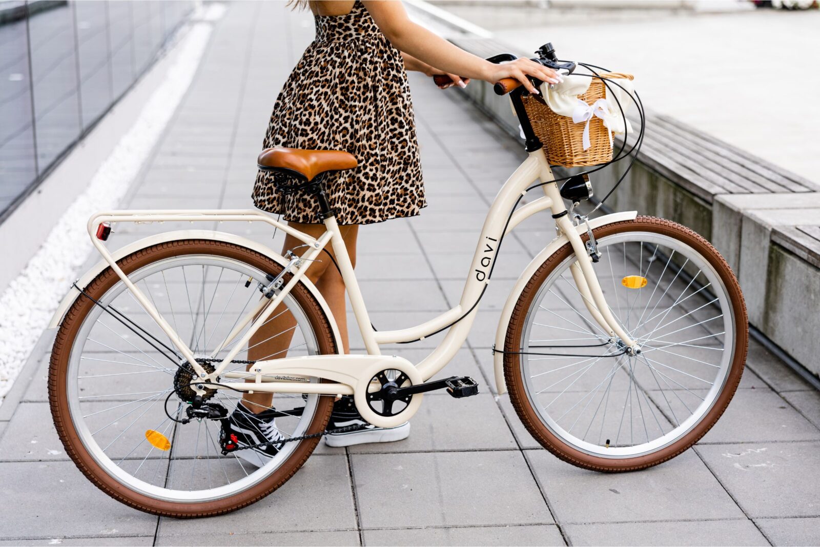 Kvinna med leopardklänning bredvid vit cykel