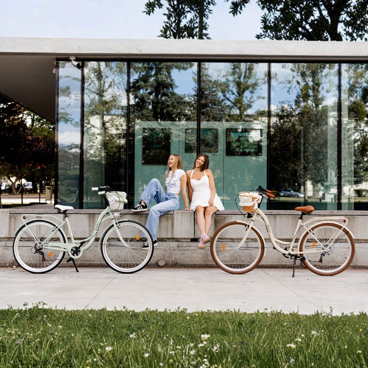 Dve ženy s bicyklami pred modernou budovou