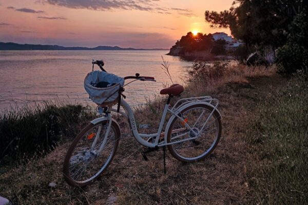 Solnedgång vid havet med cykel längs kust.