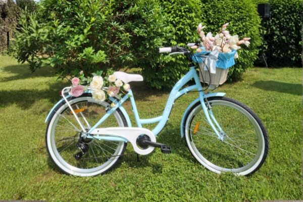 Blå cykel med blommor i en trädgård.