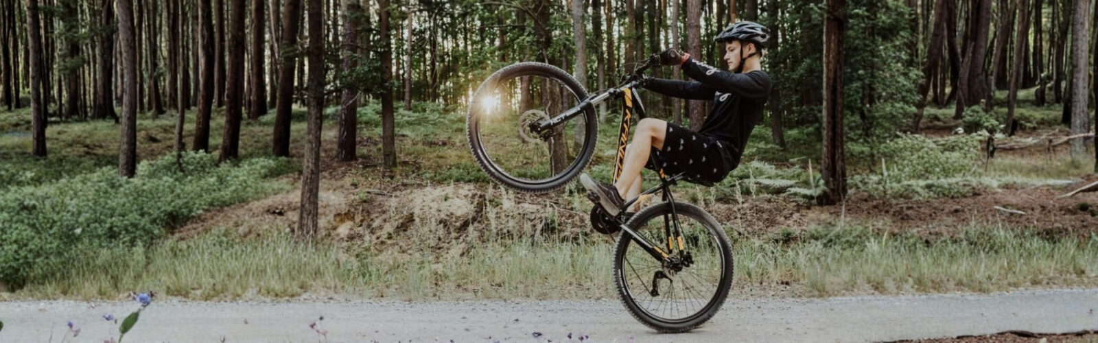 Cyklista vykonáva akrobatický trik v lese.